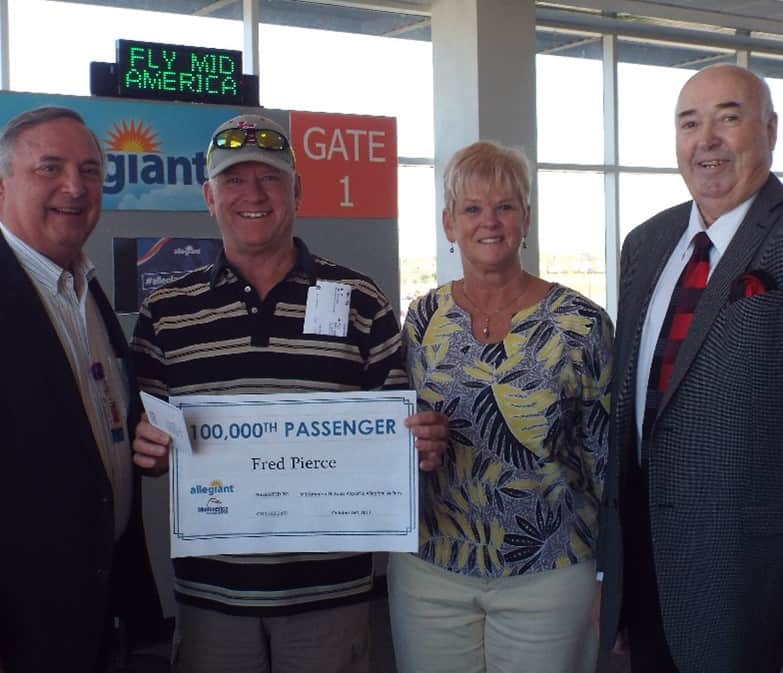 Allegiant 100,000th passenger in 2017 holding certificate with Airport Director