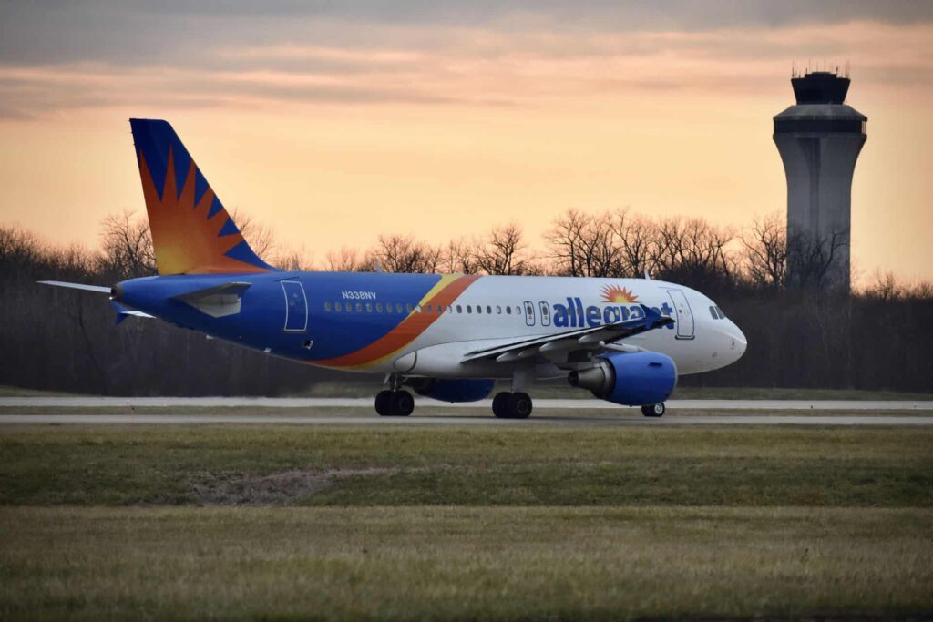 Allegiant airplane taxing for takeoff with sunset and control tower in background