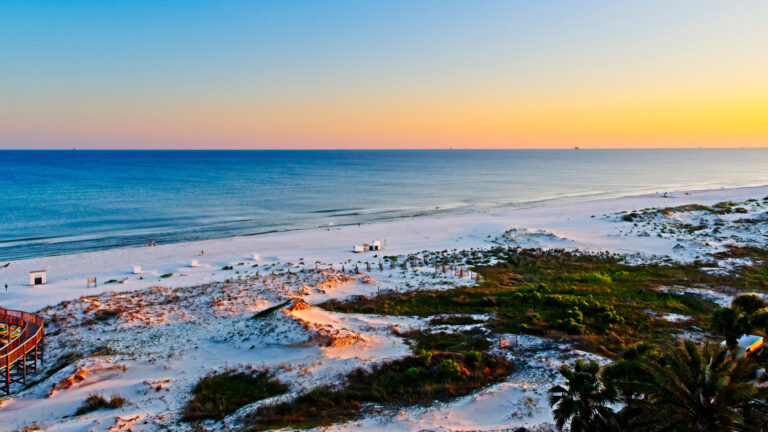 Vibrant sunset on a white sandy beach with the ocean in the background in Gulf Shores, Alabama